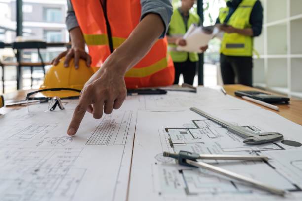 Engineers working on blueprints and construction plans. Building engineers calculate and draft building construction drawings, civil engineering, and construction business concepts.